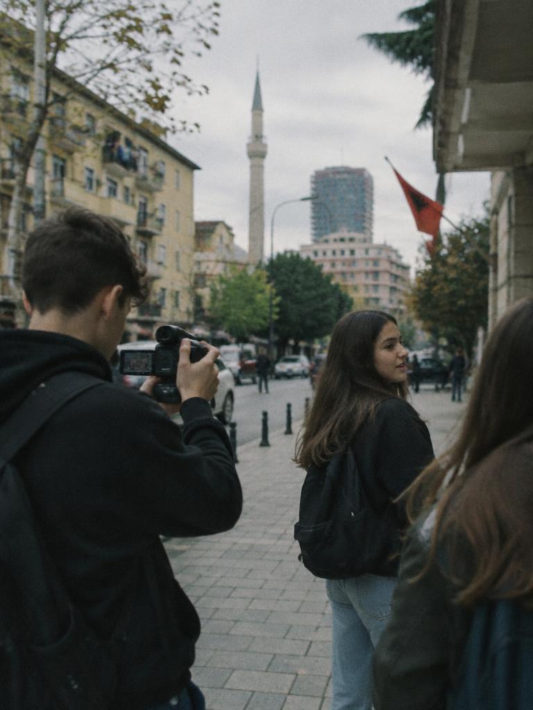 Students filming on a Tirana street with a small camera